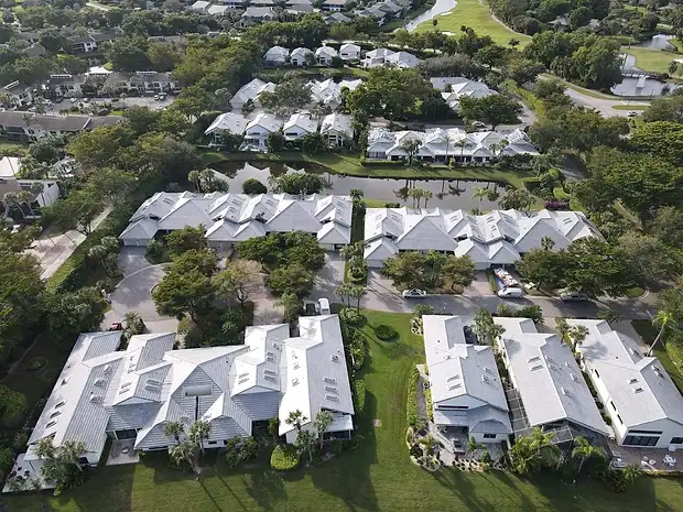 Aerial view of a coastal community with new white roofs