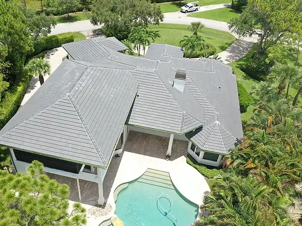 Aerial view of an estate home with a flat tile roof and pool