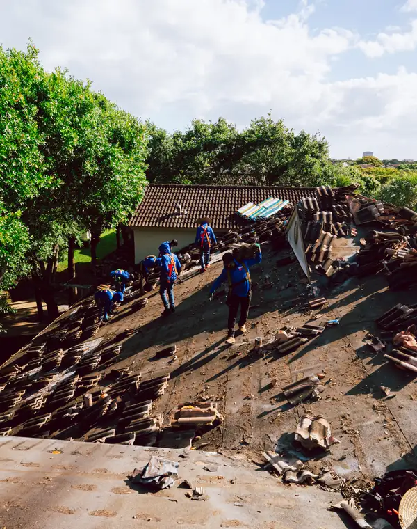 Molsbee crew in company shirts spread across a tile roof mid tear-off