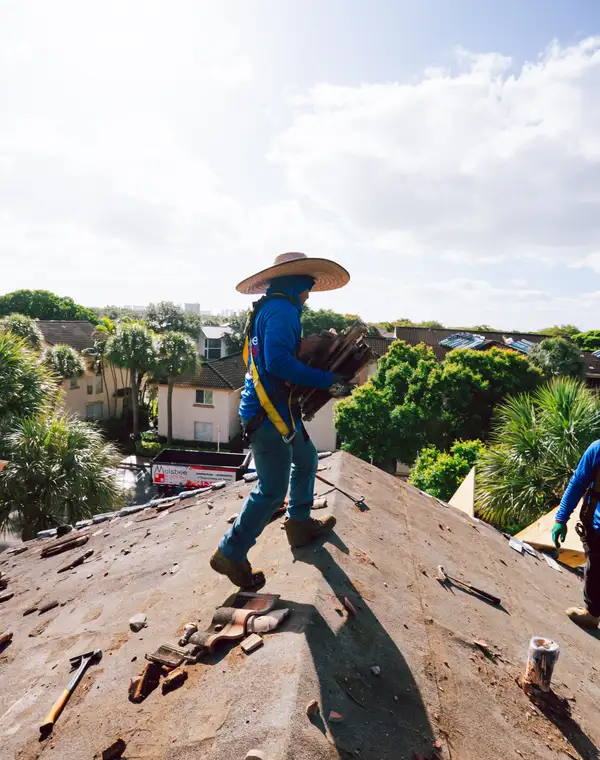 A roofer crossing the ridge of an open roof, tiles in hand