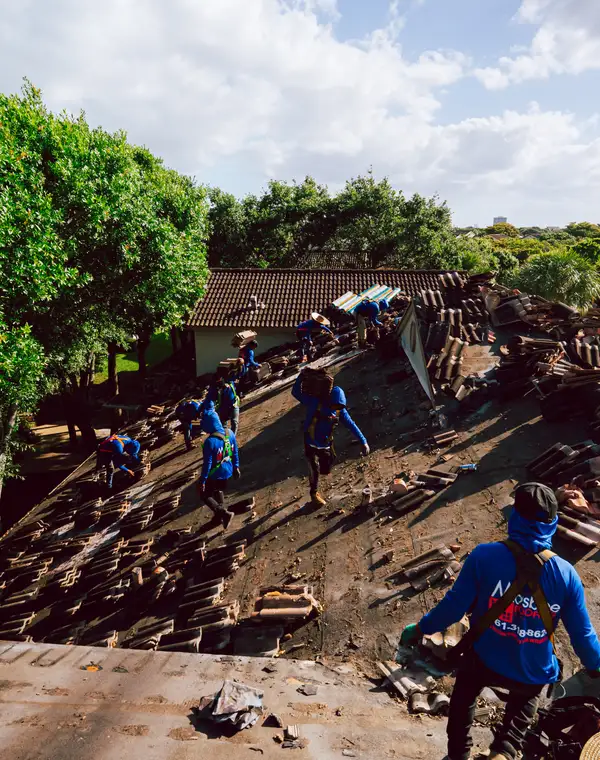 The crew working down a stripped tile roof between the trees